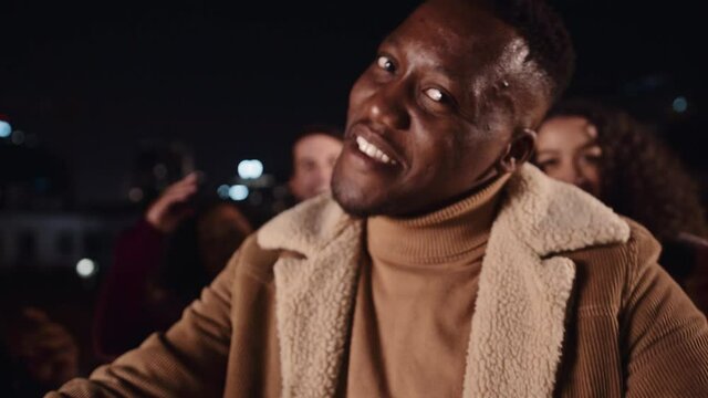 Black male dancing and smiling with friends at rooftop party in the city. High quality 4K footage