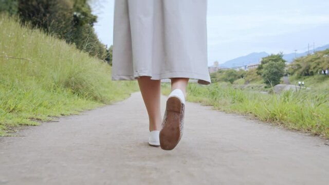 道を歩く女の子の足元。女性のスカートと靴

