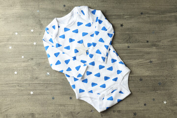 Concept of baby clothes with romper on gray textured background