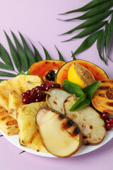 Concept of tasty food with grilled fruits on violet background.