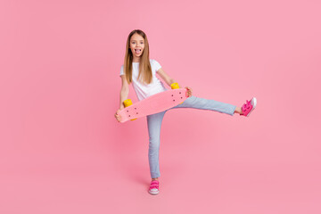 Full body photo of nice blond little girl tongue out hold skate wear white t-shirt jeans isolated...