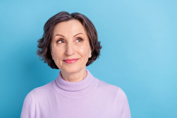 Photo of aged attractive woman happy positive smile dream think look empty space isolated over blue color background