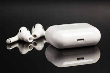 Wireless earphones in charging case on black background