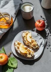 Bread slices with cottage cheese, honey, apples and nuts on the plate. Breakfast concept
