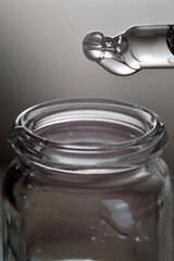 Liquid transparent gel or serum pipette with drops on gray backg