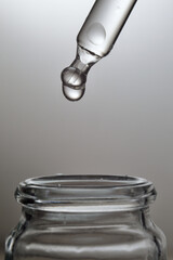 Liquid transparent gel or serum pipette with drops on gray backg