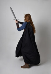 Full length, portrait of red haired woman wearing medieval viking inspired costume and flowing...