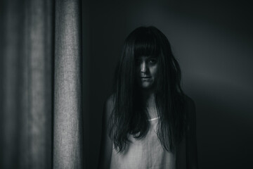 Female ghost in white dress in room. A young scary girl in an old white dress staring in to the...