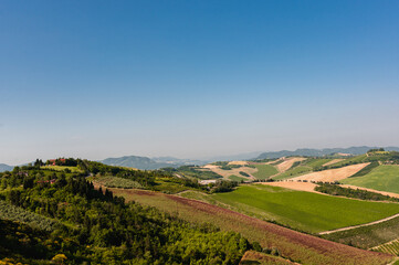 Fototapeta na wymiar Aerial view of typical Italian landscape with cultivated fields, houses and blue sky.