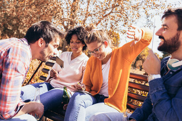 Group of young people hangout in the park.They are play guess who game.