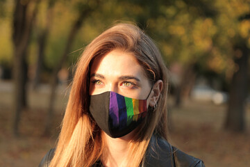 Young woman wearing gay pride mask - Lgbt rights concept. in the park. close-up portrait