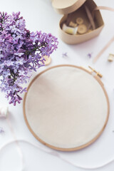 Flat lay top view photo of a mockup with embroidery hoop and llilac flowers.