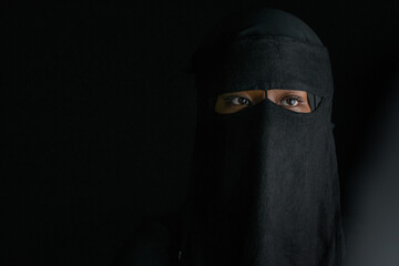 Closeup, teen girl in dress traditional Muslim style with Niqab veil, on black background