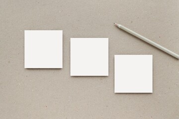 Three small square notepads or sticky notes mockup on brown craft paper for design or text presentation.