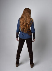 Full length portrait of red haired woman wearing medieval viking inspired costume,  standing pose...