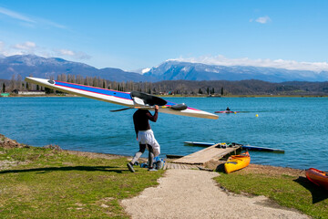 a man carries a boat on his shoulder. descent to a beautiful lake, mountain landscape