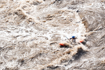 passing rapids on a mountain river by kayak. a man with an oar in a boat rowing in the stormy waters of the river