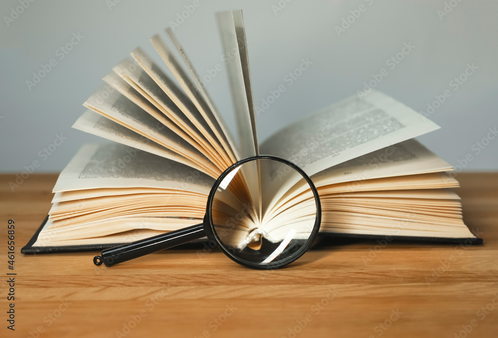 Poster magnifying glass and open books with turning pages on wood table. reading and studying concept.