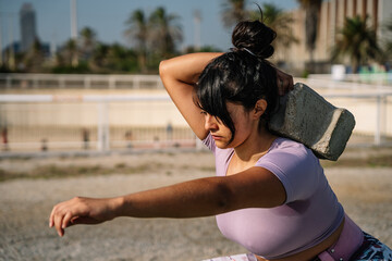 Strong Hispanic sportswoman lifting concrete block during outdoor functional workout