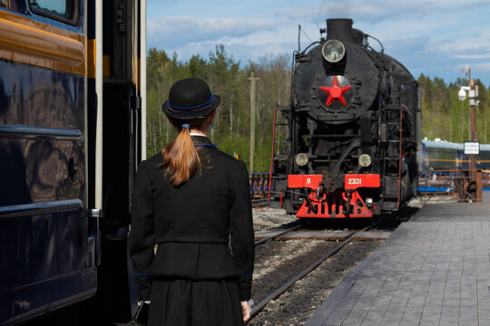 the conductor stands with her back next to the train