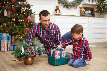 Obraz na płótnie Canvas Little boy with his father near fir-tree. Christmas celebration. Boy with Dad weared in red checkered shirts. New year eve