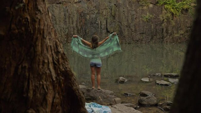 Tree Trunk Revealed A Woman With Scarf Stretching Her Arms - Rocky Waterhole In Cedar Creek Falls In QLD Australia. Dolly Shot