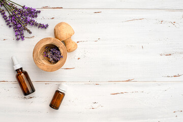 lavender oil in glass bottles, lavender flowers on rustic wooden background