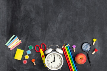 school stationery supplies, clock and apple on blackboard background. back to school concept