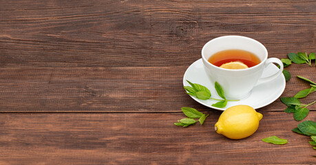 Fototapeta na wymiar cup of tea with lemon and mint in white cup on wooden brown background