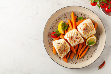 Fried pieces of cod loin, served with sweet potato fries. Light stone background.