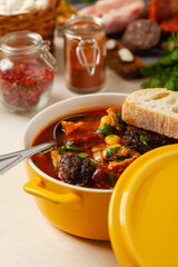 Traditional Spanish goulash soup. Fabada Asturiana. Served with a yellow clay pot with lid. Front view.