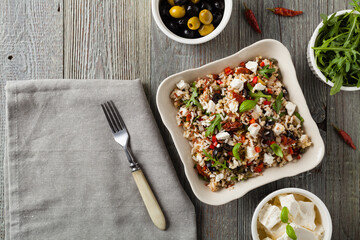 Trendy lunch with red rice, a mix of groats and vegetables. Top view. Served in white bowl on grey wooden background.