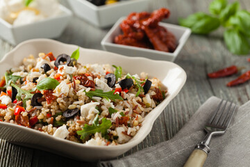 Trendy lunch with red rice, a mix of groats and vegetables. Front view. Served in white bowl on grey wooden background.