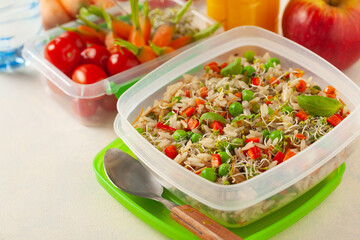 Trendy lunch with rice and vegetables. Served in a portable box on a bright painted background. Perfect for work or school. Front view.