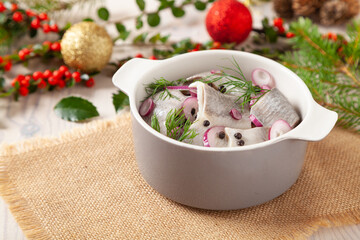 Herring fillets in oil. Served with onion in a bowl. Wooden background.