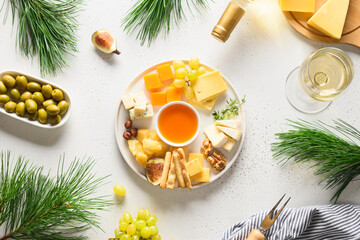 Christmas party with cheese platter, white wine, olive, different cheese, fruits on a white background. Top view. Appetizer for party.