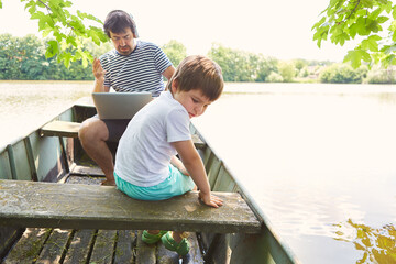 Naklejka na ściany i meble Child in a boat on the lake on summer vacation