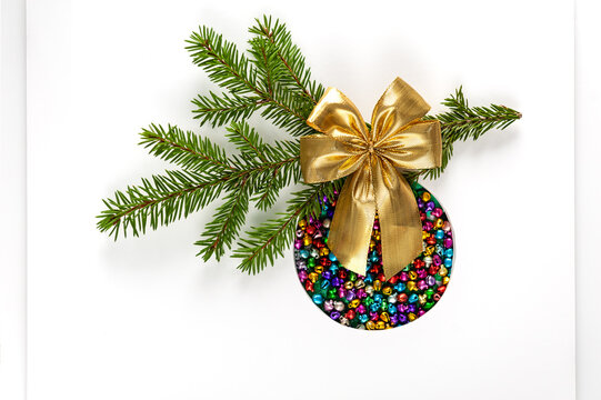 Christmas tree toy made of colored sleigh bells with gold bow on white background. Background for greeting card, poster. Soft focus, copy space.