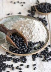 Plate with black beans flour with a wooden scoop
