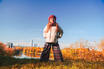 little girl in a beret and autumn clothes on an autumn background. Smiling kid play in autumn park. High quality photo