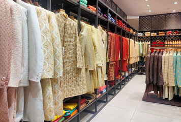 Pune ,INDIA, 2 October 2021 : Indian men latest fashion dress hung on hangers, in display in retail shop in market, wedding wear for men India