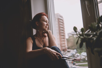 A beautiful girl in a bodysuit sits on the window, black and white photo.	
