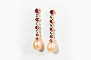 Long gold earrings with diamonds, rubies and pearls, on a white background