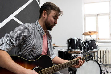 Male musician is playing music on wooden acoustic guitar, capture chords by finger.