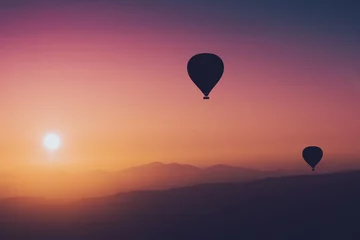 Fototapete Rosa Heißluftballonsilhouetten mit aufgehender Sonne über den Bergen