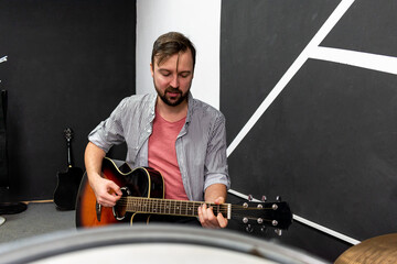 Male musician is playing music on wooden acoustic guitar, capture chords by finger.