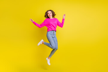 Fototapeta na wymiar Full length photo of pretty charming curly young lady dressed pink pullover jumping high isolated yellow color background