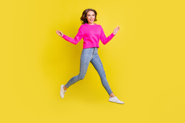 Fototapeta na wymiar Full length photo of sweet adorable wavy young woman wear pink sweater jumping walking isolated yellow color background