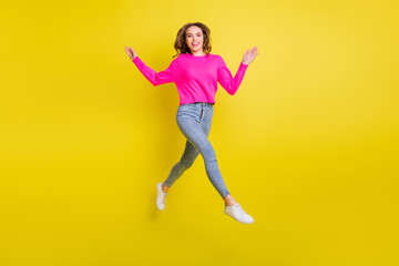 Fototapeta na wymiar Full length photo of charming shiny curly young lady dressed pink pullover walking jumping high isolated yellow color background