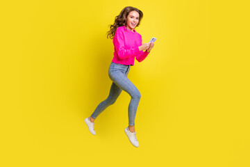 Fototapeta na wymiar Full length photo of shiny lady dressed pink pullover walking jumping high typing modern device isolated yellow color background